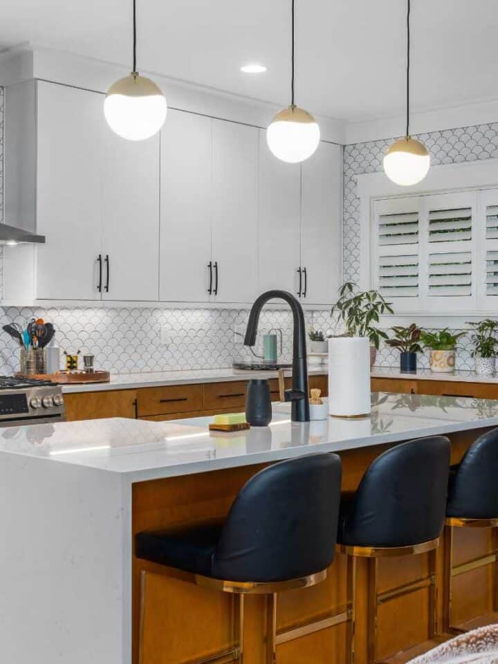 Bright kitchen featuring white cabinetry, black seating, and pendant lighting.