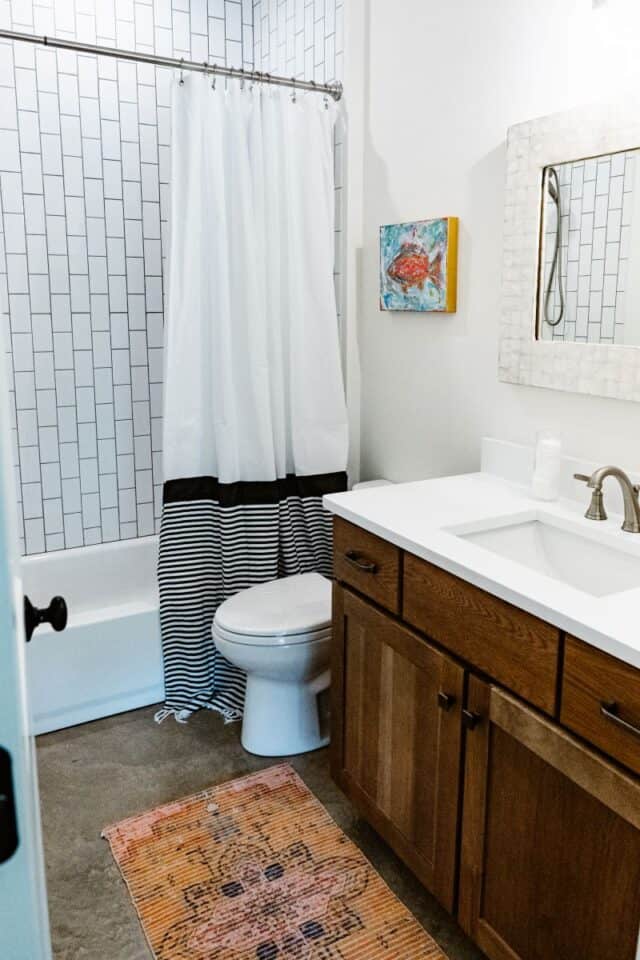 Modern bathroom with white subway tiles and wooden vanity.