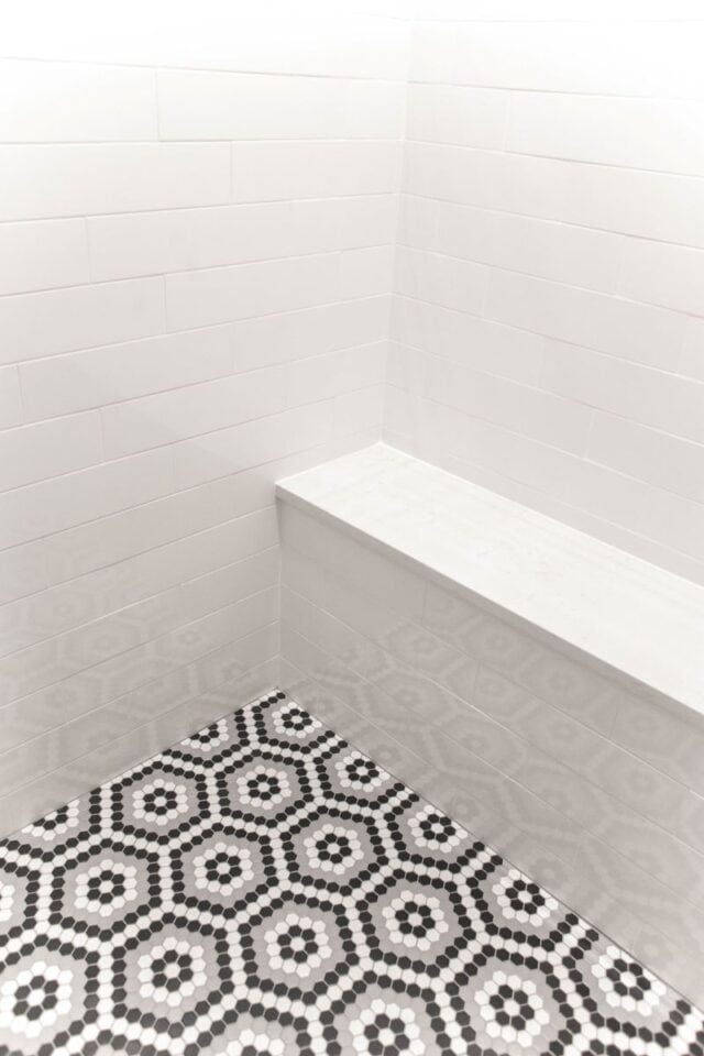 Modern Pelham primary suite bathroom with sleek white tiles and patterned floor.