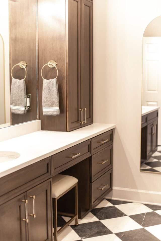 Primary bathroom vanity with dark wood cabinets and gold hardware for Pelham suite.