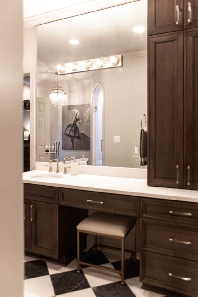 Modern primary suite bathroom with elegant dark cabinetry and luxurious lighting.