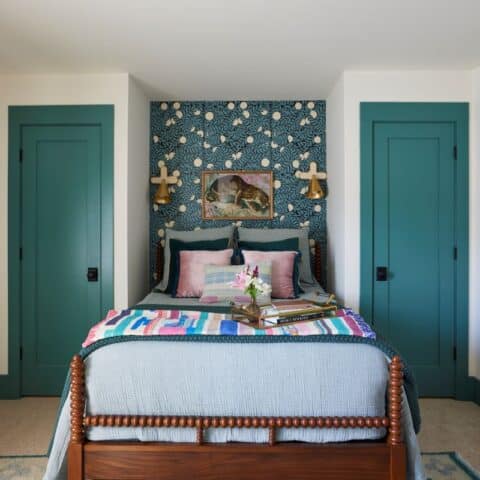 Inviting guest nook featuring a bed with colorful bedding and a patterned accent wall.
