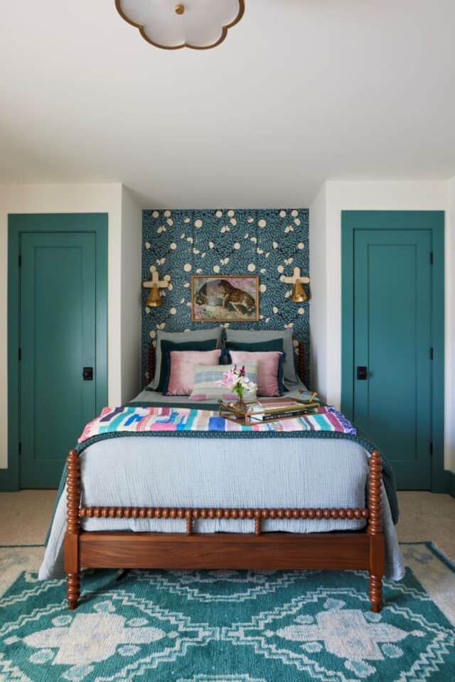 Inviting guest nook featuring a bed with colorful bedding and a patterned accent wall.