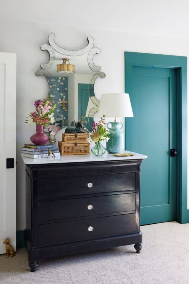 Elegant guest nook featuring a black dresser, mirror, and floral decor for a welcoming 2024 Birmingh.