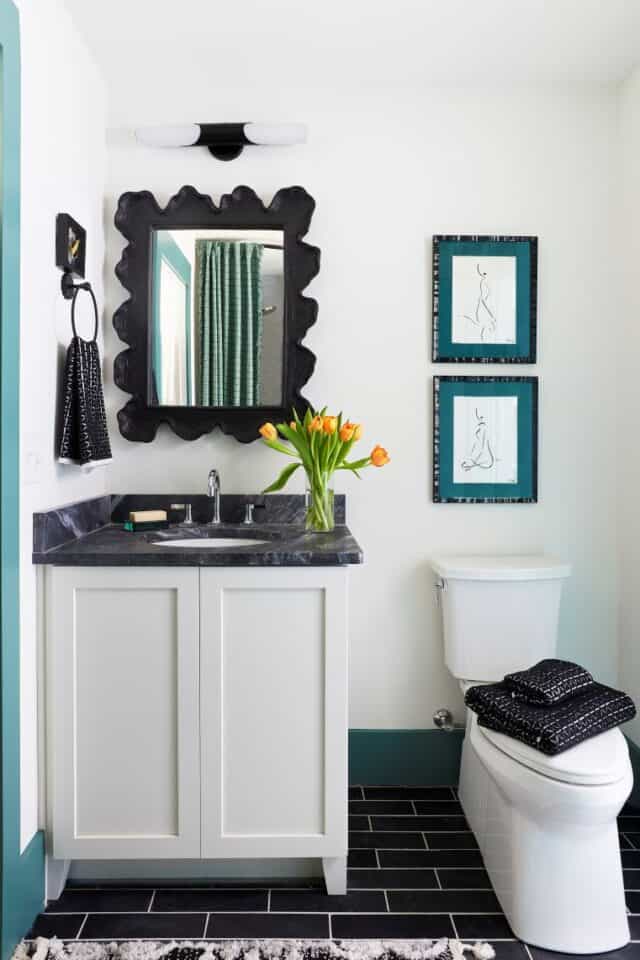 Bathroom vanity with black-framed mirror and artwork.