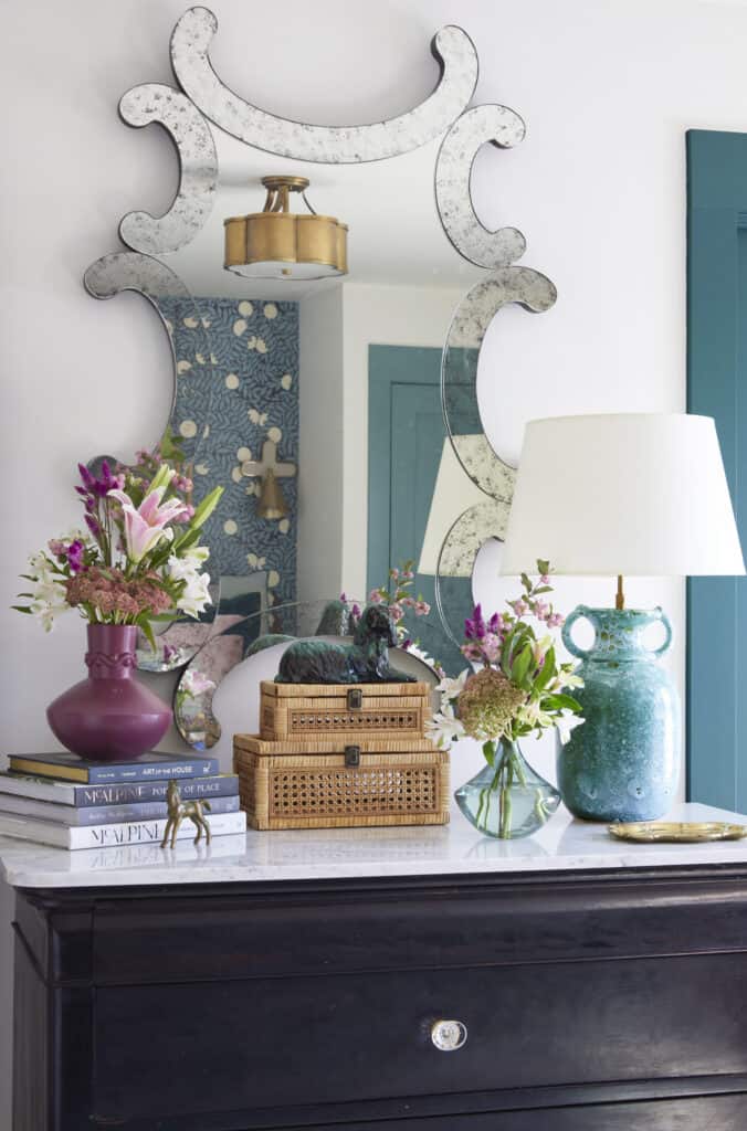 Colorful guest nook with floral arrangements, mirror, and decorative accents for inviting space.