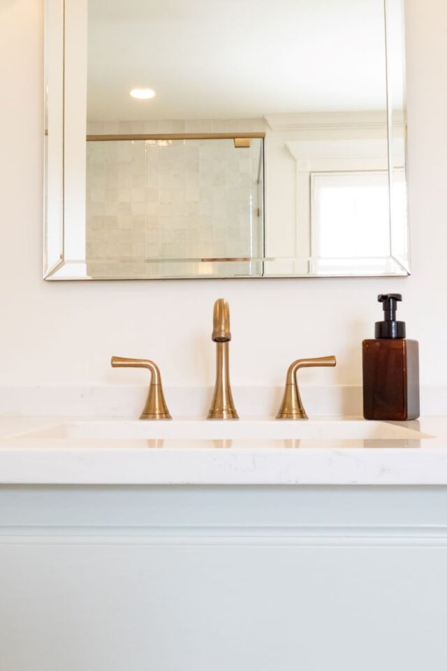 Elegant bathroom sink with gold fixtures and mirror.