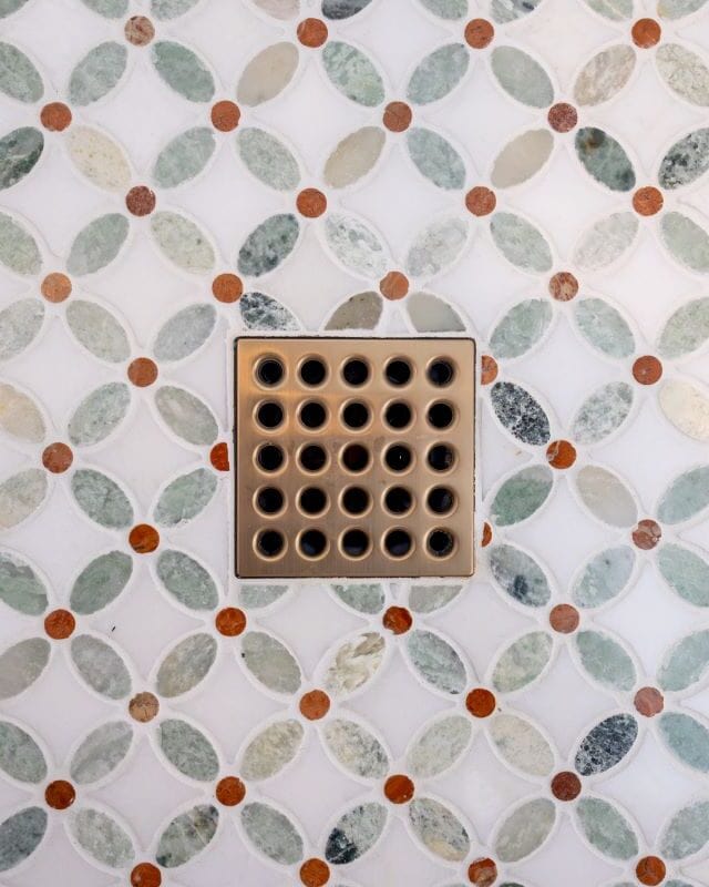 Decorative bathroom tile with a central drain cover in Highland Lakes renovation.